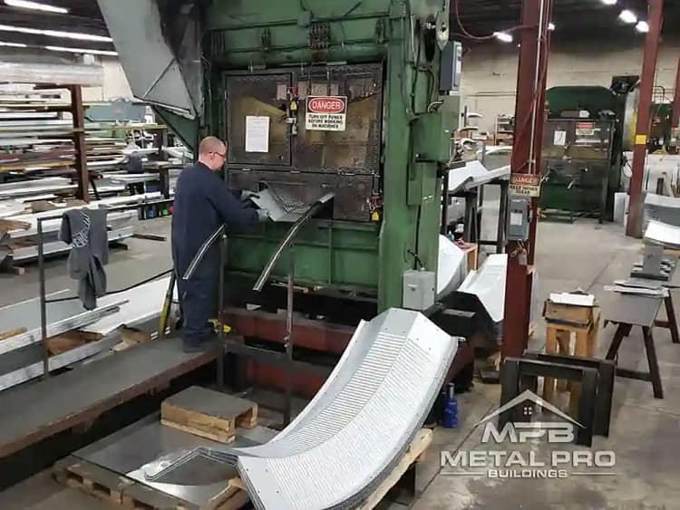 Home 13 Worker operating industrial press forming curved steel panels at MPB Metal Pro Buildings.